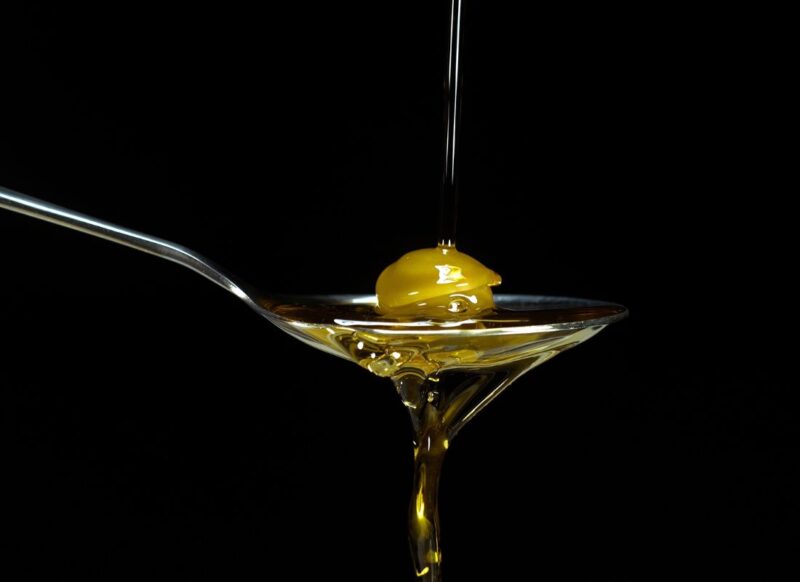 prikaz kašike u kojoj je maslina i maslinovo ulje koje curi iz nje