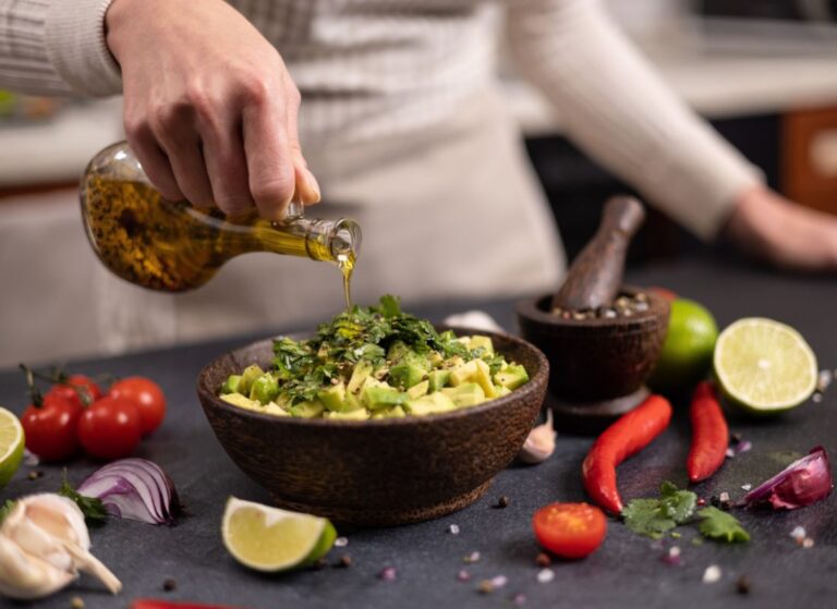 prikaz osobe koja začinjava salatu od avokada sa maslinovim uljem